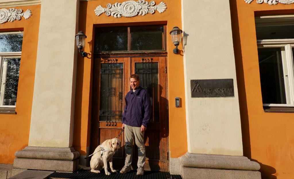 Riku seisoo Åbo Akademin oven edessä Kille vierellään. Ovessa on ikkunat, joiden edessä on rautakoristeet. Oven yläpuolella on oven levyinen kipsikoriste. Oven molemmilla puolilla on seinälamput.