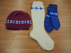 punainen myssy, valkoiset sukat, siniset käsineet, kaikissa koristeena Suomen lippuja