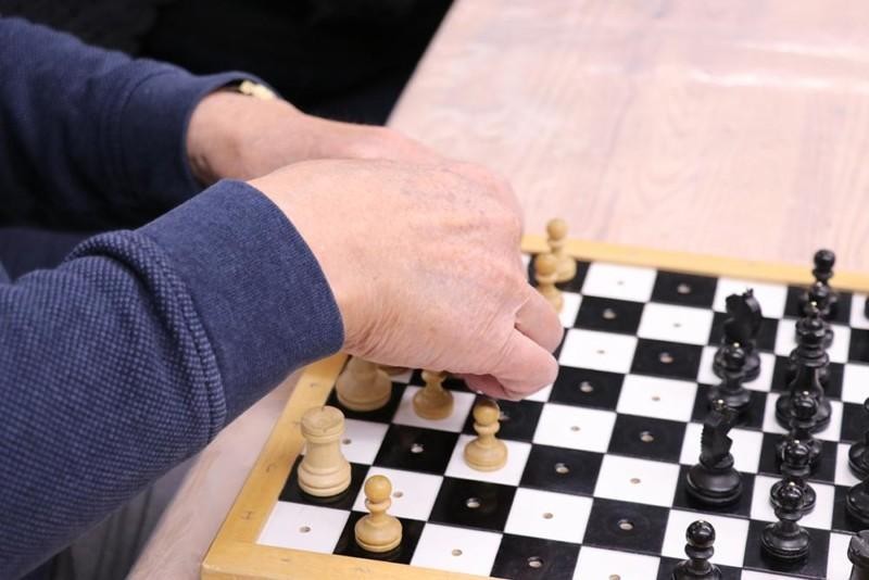 Lähikuva käsistä, jotka siirtävät shakkinappuloita näkövammaisten shakkilaudalla.