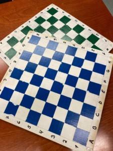 Kaksi shakkilautaa, jossa on valkoisia ja mustia ruutuja Ruuduissa on myös reikiä.