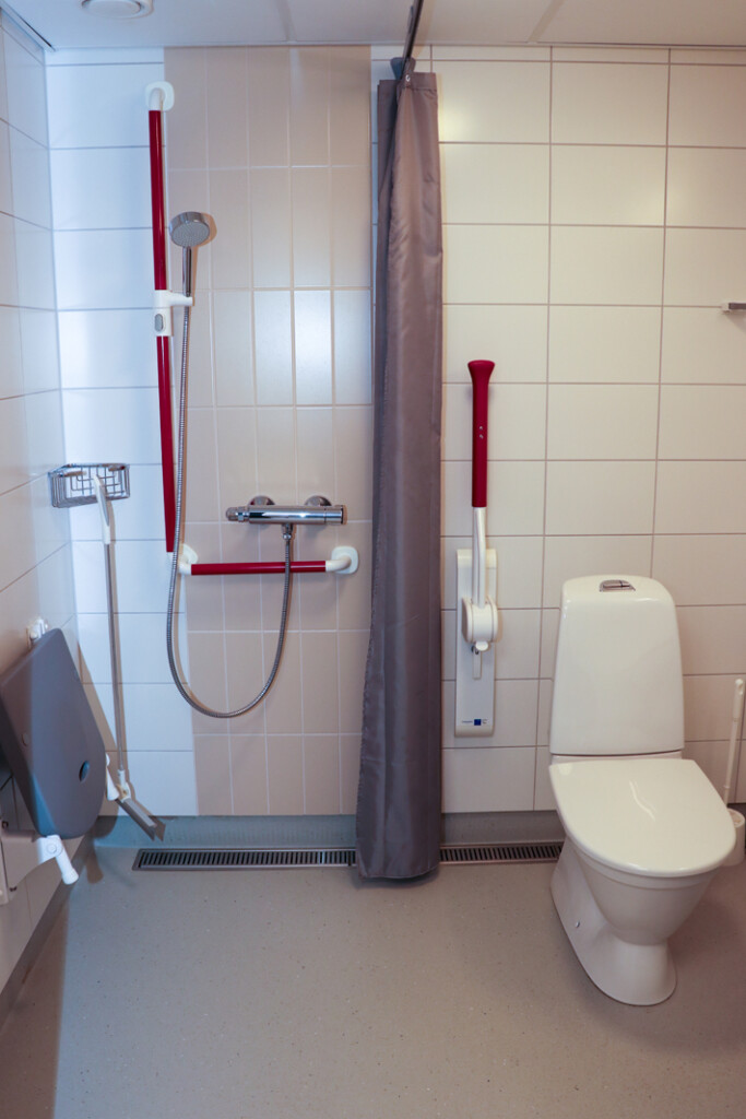 WC-tilat. Istuimen ja suihkun yhteydessä ovat nojatuet.