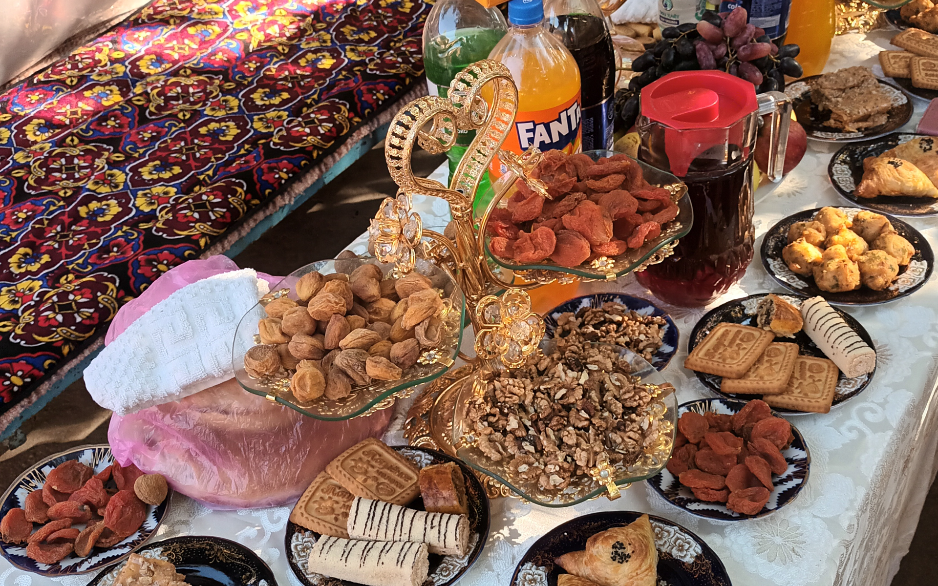 Pöydällä on useita lautasia täynnä erilaisia ruokia. Esillä on myös juomapulloja, kuten Fanta.