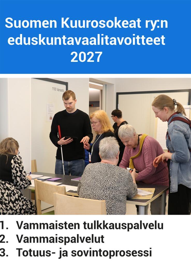 Henkilöitä äänestystilanteessa. Kaksi henkilöä istuu pöydän ääressä, neljä seisoo pöydän edessä. Yhdellä henkilöllä on kädessään valkoinen keppi. Alaosassa on lueteltu teesit.